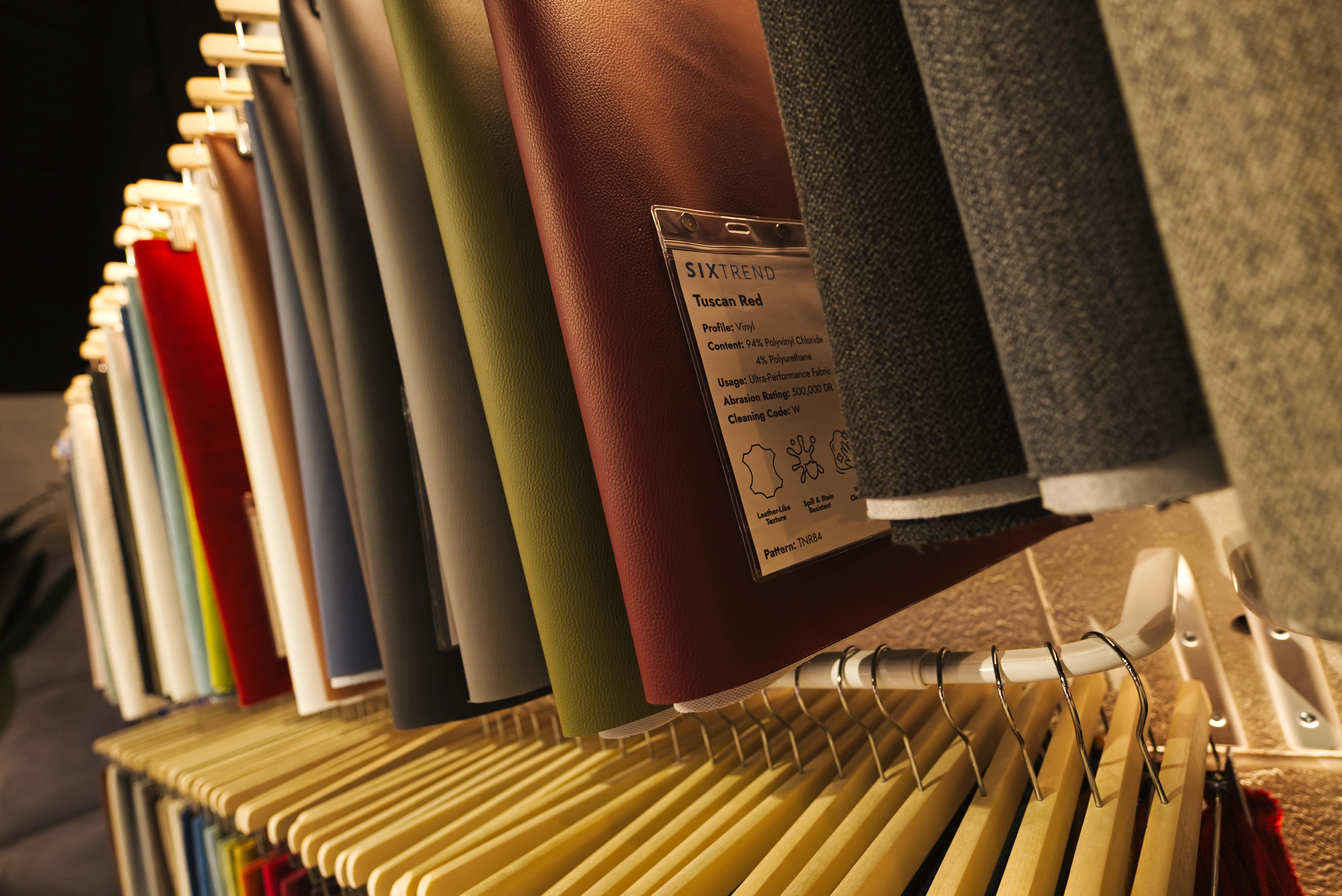 SIXTREND showroom fabric swatch display rack with leather, wool, and woven samples on wooden hangers