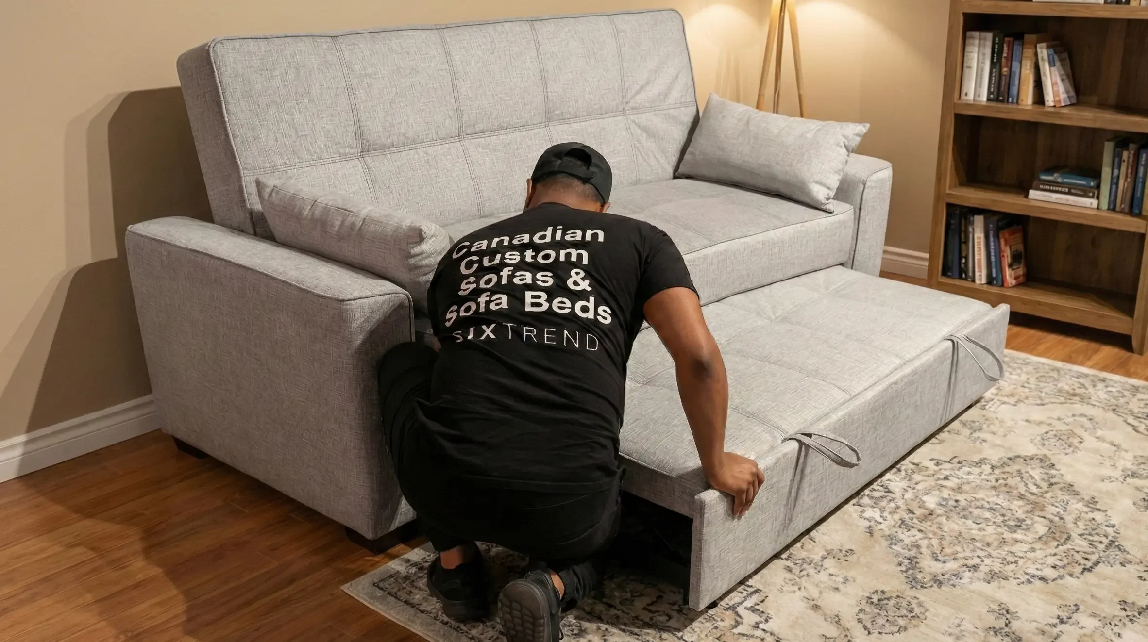 SIXTREND delivery technician in a SIXTREND-branded shirt setting up a custom sofa bed's trundle in a customer's living room