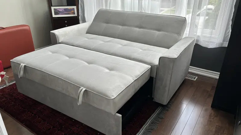 A SIXTREND Flex sofa bed with extended trundle in a customer's home, displaying upholstery colour options against a hardwood floor and patterned area rug.