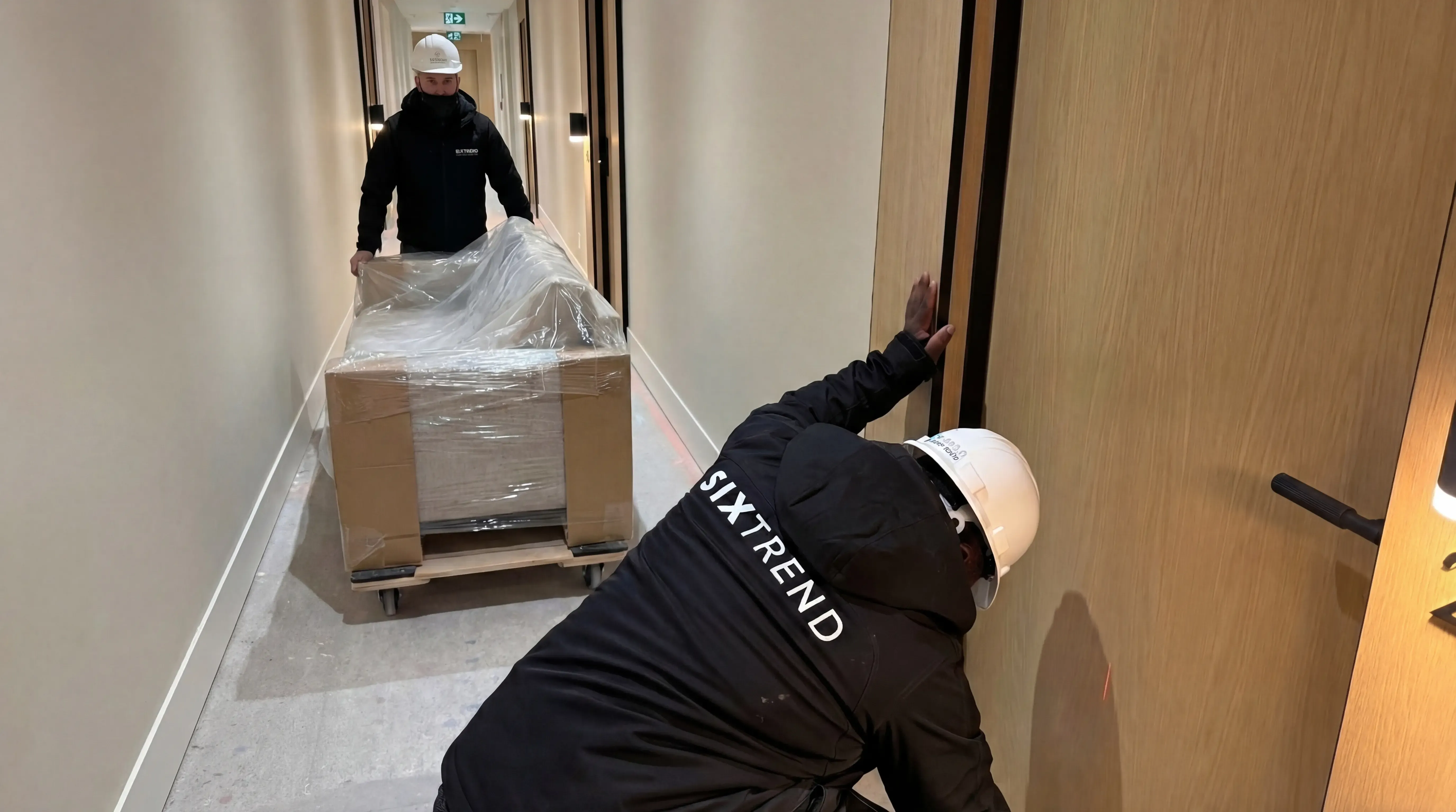 SIXTREND delivery team moving a wrapped sofa into a building