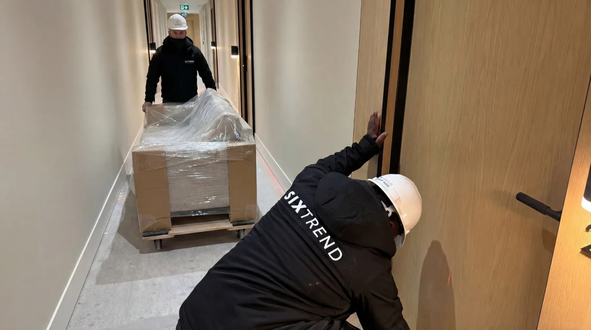 SIXTREND delivery team moving a wrapped sofa into a building